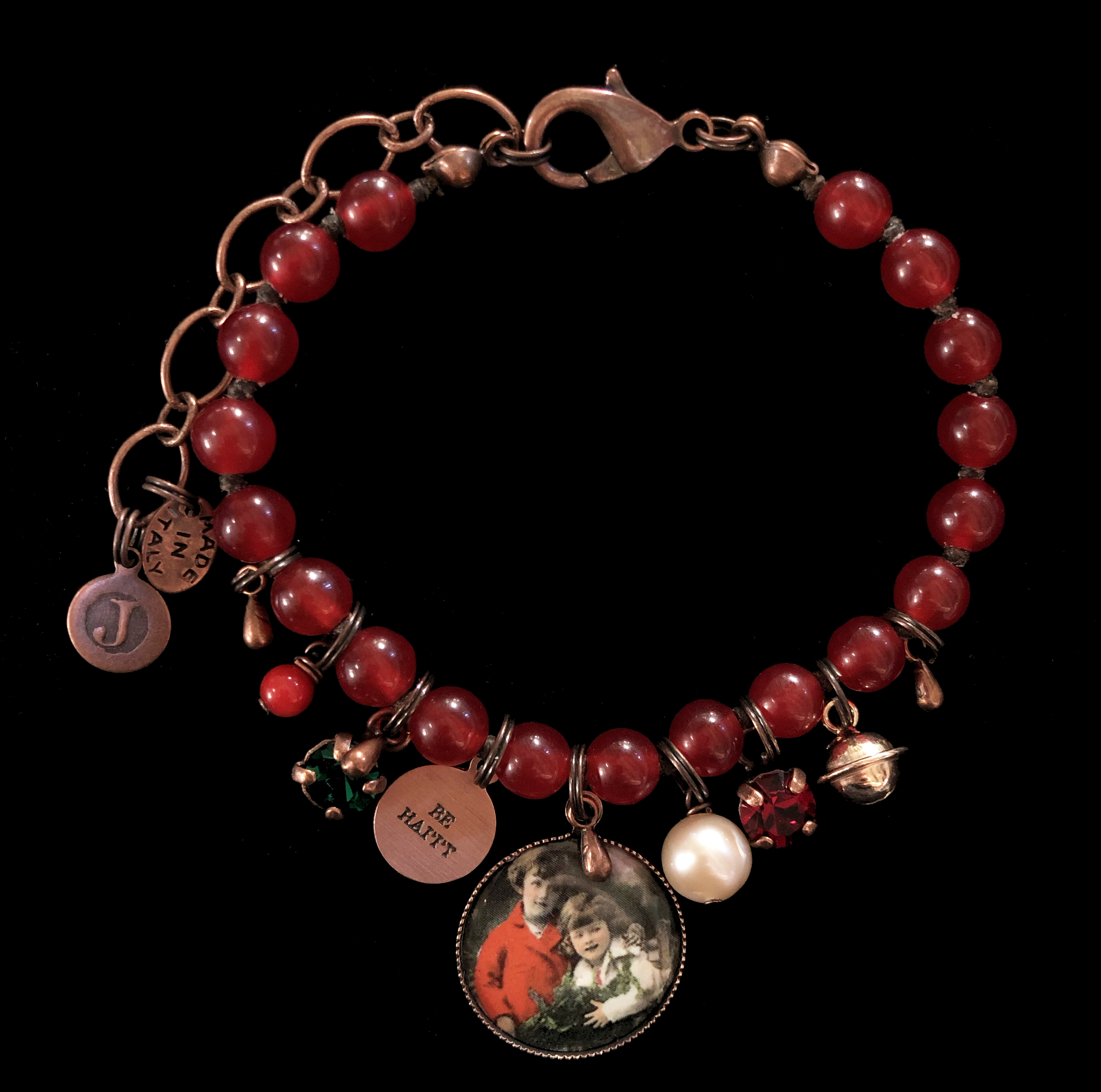 Bracciale in pietre rosse con medagliette in porcellana, rame, cristalli e pietra in madreperla.